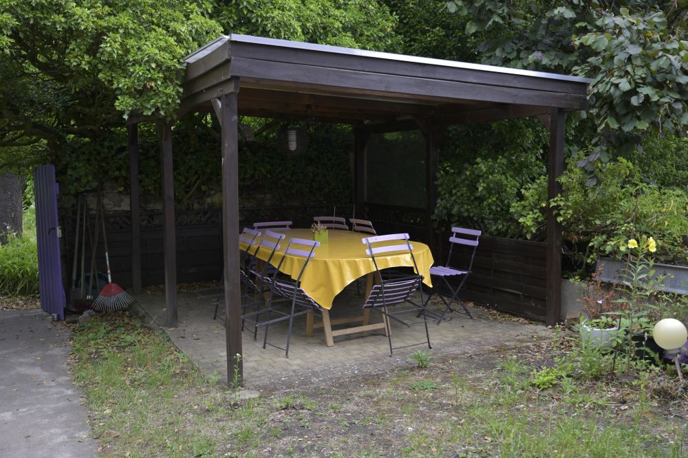 L'abri du jardin, sa table à la nappe jaune et ses chaises de jardin