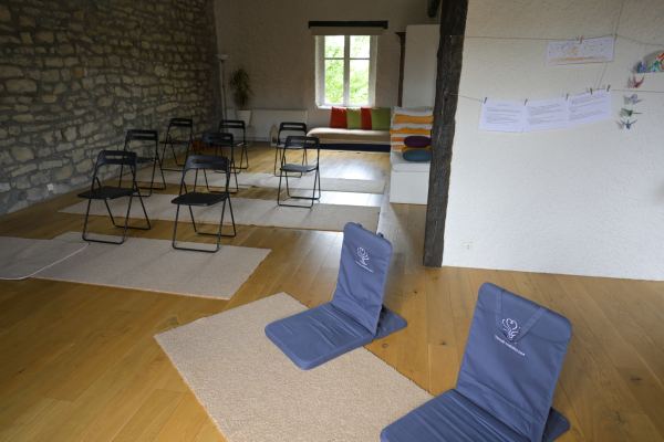 Des assises de méditation posées sur des tapis, devant des chaises pliantes