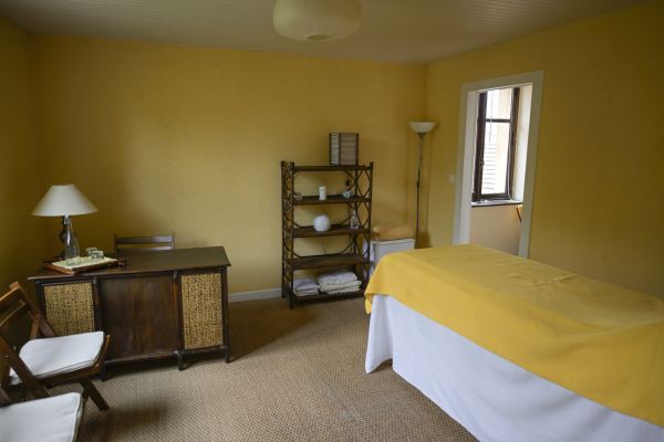 Une salle de soins aux murs jaunes, avec une table de massage