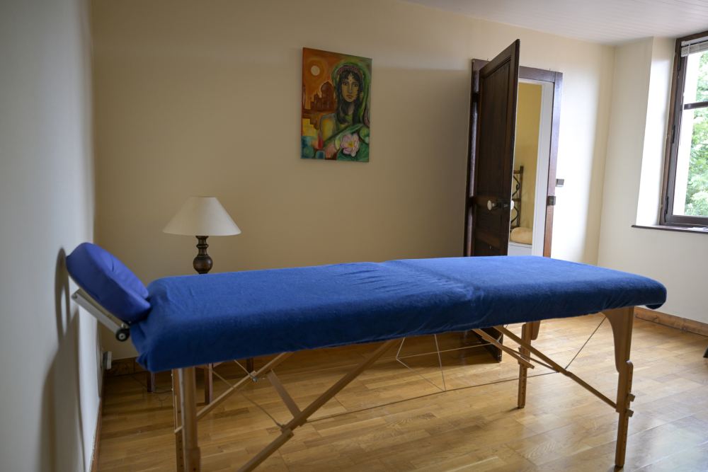 Une salle de soins claire au parquet de bois, avec une table de massage bleue